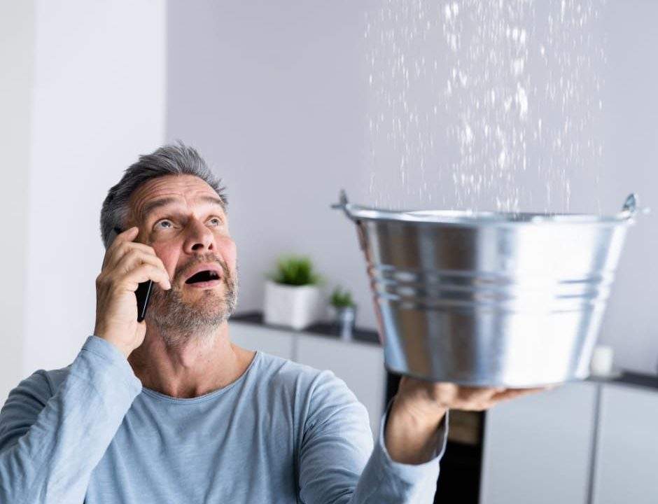 a homeowner experiencing a roof leak while on the phone with an Ottawa roof repair company