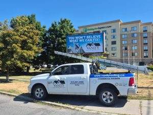 a Vanity Roofing truck in front of a Vanity Roofing billboard in kingston