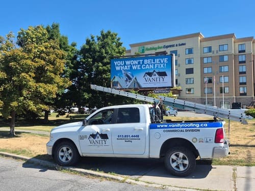 Vanity Roofing truck in front of a Vanity Roofing billboard ad